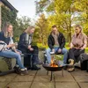 Four people are sitting around a fire pit, roasting marshmallows. Produktbild-Vorschau
