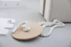 A close-up of a wooden disc swing with a rope attached, resting on a light gray surface. Voir les images du produit