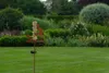 A garden stake with a solar-powered lantern and a rain gauge is placed in a lush green lawn, with a well-maintained garden in the background. Anteprima dell’immagine prodotto