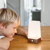 A young boy is looking at a small, illuminated lamp on a wooden table. Anteprima dell’immagine prodotto