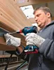 A man is using a Bosch cordless drill to fasten a screw into a wooden beam. Produktbild-Vorschau