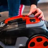A person's hand is adjusting a dial on a black and orange vacuum cleaner. Anteprima dell’immagine prodotto