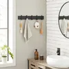 A bathroom scene with a wall-mounted coat rack holding various bathroom accessories, a sink, and a cabinet. Produktbild-Vorschau
