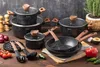A collection of cookware and kitchen utensils arranged on a wooden surface with a dark textured background. Produktbild-Vorschau