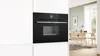 A modern black oven integrated into a white kitchen cabinet, with a dining area visible through a doorway in the background. Anteprima dell’immagine prodotto