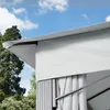 A close-up view of a grey gazebo roof and side panels against a blue sky with clouds and trees in the background. Produktbild-Vorschau