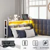 A bed with a headboard featuring integrated storage and LED lighting, shown with decorative items and a tablet. A close-up of an electrical outlet with USB ports is in the foreground. Podgląd zdjęcia produktu