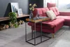 A modern living room with a red sectional sofa, a wooden and metal side table, and decorative items on a shelf. Produktbild-Vorschau