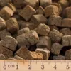 A close-up view of dry pet food kibble with a ruler at the bottom. Anteprima dell’immagine prodotto