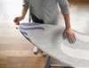 A person is adjusting an ironing board cover. Podgląd zdjęcia produktu