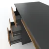 A close-up, angled view of a modern desk with three drawers partially open, revealing wooden drawer fronts and metal drawer slides. The desk surface is a matte gray. Produktbild-Vorschau
