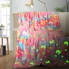 A colorful unicorn-themed blanket draped over a sofa, with a lamp and a window in the background. Náhľad obrázku produktu