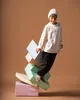 A young boy is playfully balancing on a stack of colorful foam blocks. Podgląd zdjęcia produktu