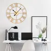 A gold Roman numeral wall clock is displayed on a white wall above a white desk with a laptop, a desk lamp, and some office supplies. Voir les images du produit