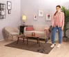 A woman is vacuuming a living room with a cordless vacuum cleaner. Voir les images du produit