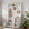 A white entryway storage unit with a bench, shelves, and cabinets, decorated with a coat, hat, bags, and plants. Produktbild-Vorschau