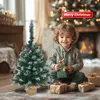 A young boy sits on the floor in front of a fireplace, holding a Christmas gift, surrounded by presents and a small artificial Christmas tree. Anteprima dell’immagine prodotto