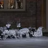 Illuminated reindeer and sleigh decorations in the snow outside a house. Podgląd zdjęcia produktu
