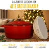 A red Dutch oven and a bread proofing basket are displayed on a wooden surface with a blurred Christmas tree in the background. Voir les images du produit