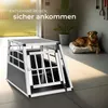 A dog crate is shown in a home environment with a dog resting on a bed nearby. Náhled obrázku produktu