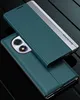 A teal and silver flip case for a smartphone is displayed on a dark, reflective surface. Produktbild-Vorschau