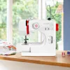 A white sewing machine is placed on a wooden surface in front of a window with greenery visible outside. Produktbild-Vorschau