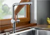 A hand operating a modern kitchen faucet in front of a window. Náhled obrázku produktu