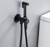 A black bidet sprayer and faucet mounted on a light gray wall next to a white toilet. Podgląd zdjęcia produktu