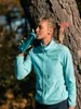 A woman is leaning against a tree and drinking from a water bottle. Anteprima dell’immagine prodotto