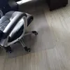 A clear plastic chair mat is placed on a light wood-grain floor, with a black and gray office chair positioned on top of it. Náhled obrázku produktu