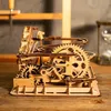 A wooden mechanical marble run toy is displayed on a wooden surface, with an hourglass in the background. Náhľad obrázku produktu