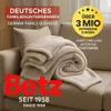 A folded blanket is placed on a sofa, with marketing text and logos overlaid. Produktbild-Vorschau