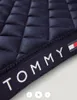 A close-up view of a quilted navy blue saddle pad with a Tommy Hilfiger branded ribbon along the edge. Produktbild-Vorschau