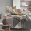 A neatly made bed with a geometric patterned duvet cover and pillows, set in a modern bedroom with shelves in the background. Produktbild-Vorschau