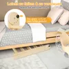 A close-up view of a wooden climbing toy set, partially assembled and placed on a floor with bedding and pillows. Produktbild-Vorschau