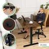 A woman is sitting at a height-adjustable desk and talking on the phone. The desk has a laptop and a cup on it. There are also close-up images of desk features. Produktbild-Vorschau