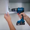 A person is using a cordless drill to attach a cabinet door hinge. Produktbild-Vorschau
