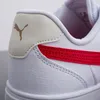 A close-up view of the heel and side of a white Puma sneaker with a red stripe. Produktbild-Vorschau
