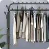 A close-up view of a black metal garment rack with various clothing items hanging on it. Anteprima dell’immagine prodotto