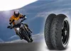 A motorcycle rider in a yellow and white suit leans into a turn on a road, with two motorcycle tires in the foreground. Produktbild-Vorschau