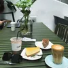 A table setting with coffee, cake, and a plant in a cafe. Produktbild-Vorschau