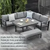 An outdoor patio set with a sectional sofa, coffee table, and bench, set on a tiled patio with greenery in the background. Produktbild-Vorschau