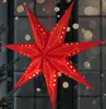 A red 3D star-shaped Christmas lantern with small yellow stars and dots, illuminated from within, hangs in front of a window with blurred lights. Podgląd zdjęcia produktu