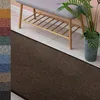 A dark brown runner rug is shown in front of a light-colored wooden floor and a grey bench with a wooden shelf underneath. A potted plant is visible to the right. Náhled obrázku produktu