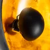 Close-up view of a lamp's internal structure, showing the bulb socket and a black shade against a textured gold background. Produktbild-Vorschau