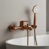 A copper-colored bathtub faucet with a handheld showerhead mounted on a wall above a white bathtub. Náhľad obrázku produktu