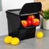 A black storage container filled with apples, with lemons on the counter in front of it. Anteprima dell’immagine prodotto