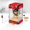 A retro-style red popcorn machine with popcorn inside and next to it, along with kernels in a bowl. Náhled obrázku produktu