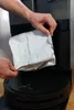 A person is holding a dust bag to insert it into a robot vacuum cleaner. Produktbild-Vorschau