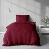 A burgundy duvet cover and pillow are displayed on a bed in a room with a brick wall. Produktbild-Vorschau